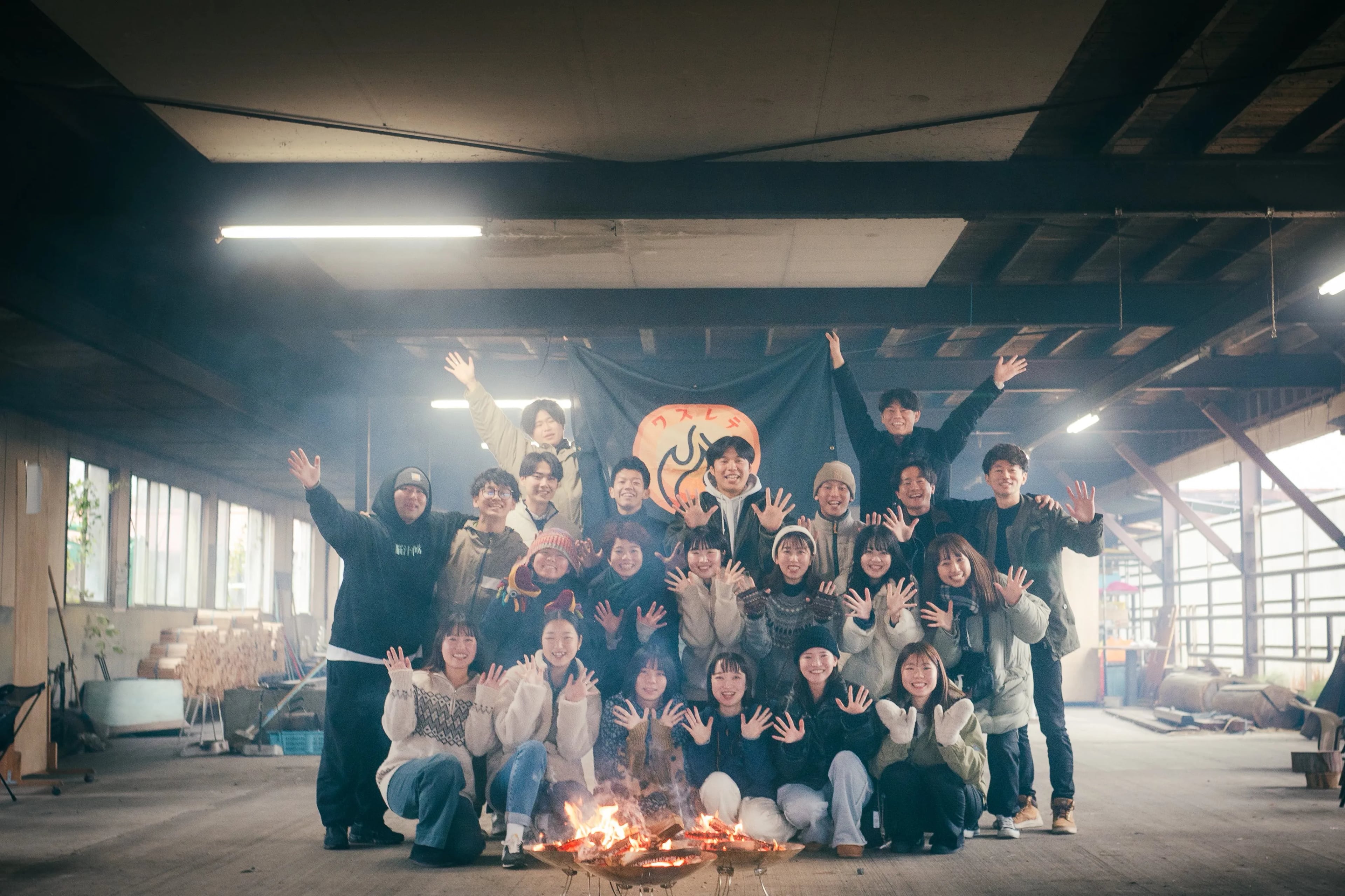 焚き火の前で手を広げて記念撮影する参加者たち